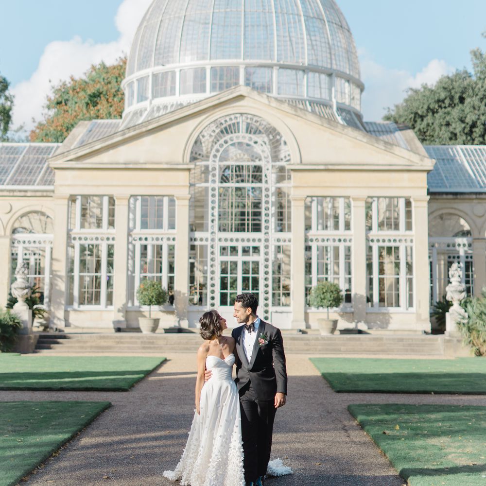 Bride & groom stand in front of Syon Park Conservatory 