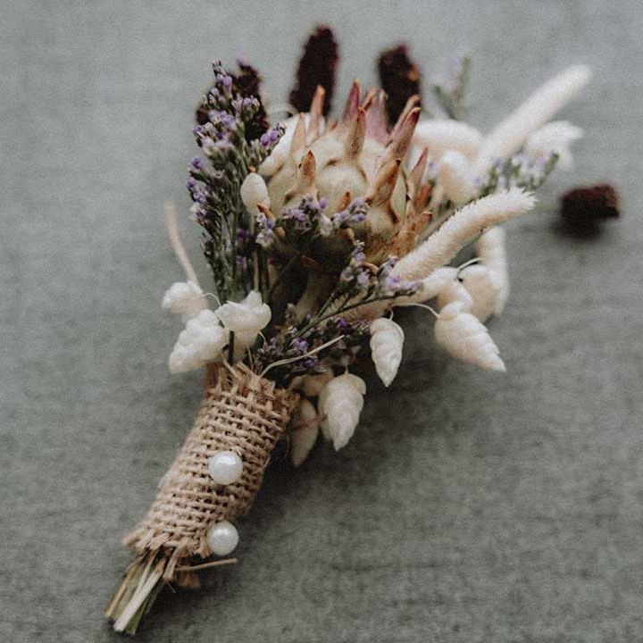 DIY wildflower buttonhole tied with brown hessian ribbon and pinned with pearl pin