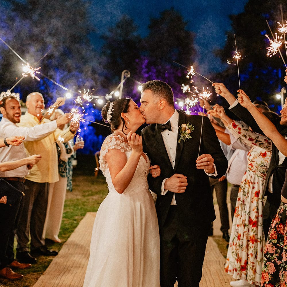 The bride and groom have a classic sparkler send off and kiss with their wedding guests waving their sparklers