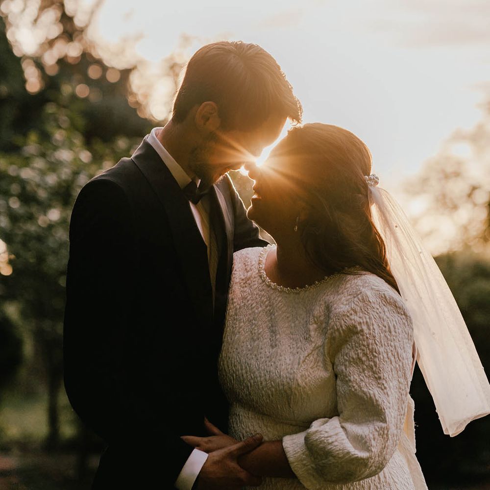 Sunset golden hour wedding photography with the bride and groom leaning in to share a kiss for monochrome minimal wedding 