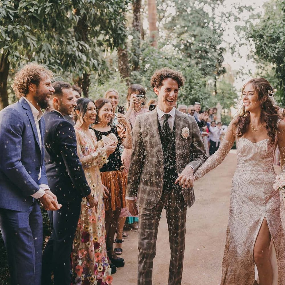 confetti moment with groom in a grey check suit and bride in a gold sparkly wedding dress