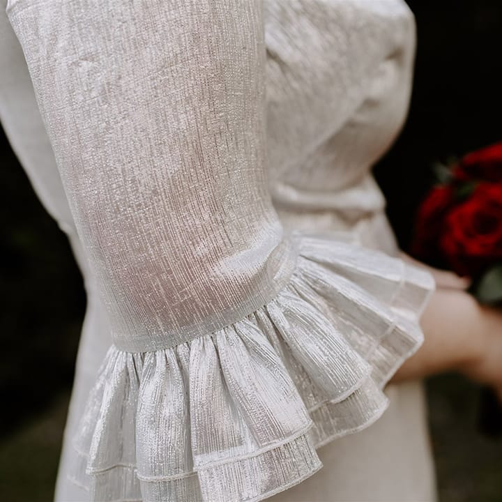 Close up of the bride's The Vamprire's Wife silver metallic wedding dress with ruffle sleeve detail 