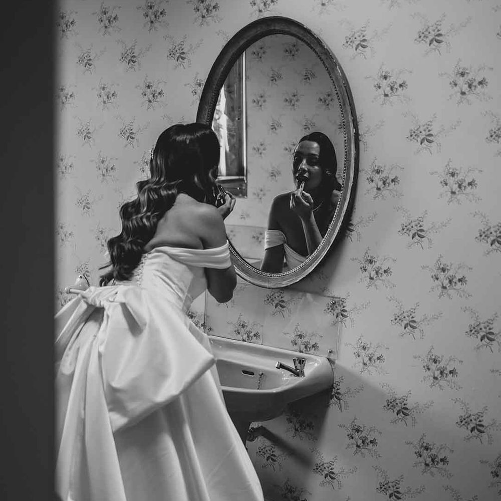 bride looking in the mirror in a strapless wedding dress with bow back detail 