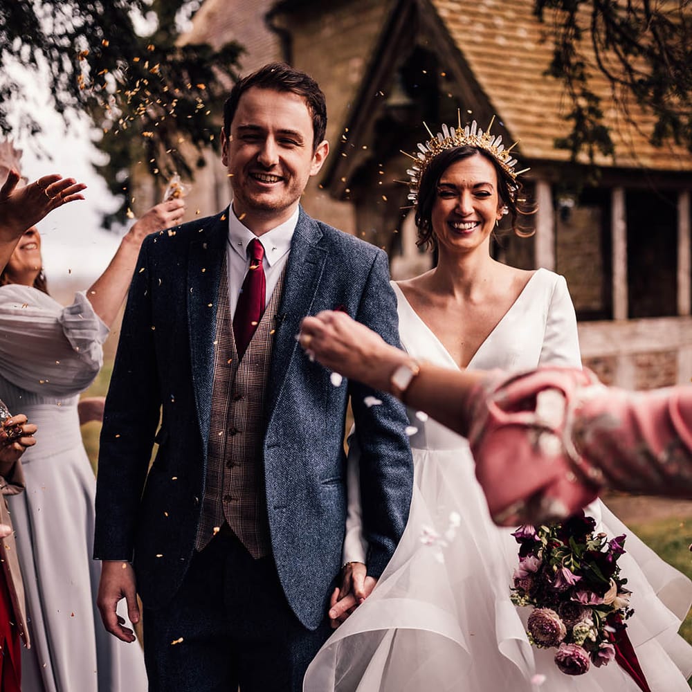 Groom in twee navy suit with checkered waistcoat with dark red tie with bride in gold crystal crown in layered wedding stationery