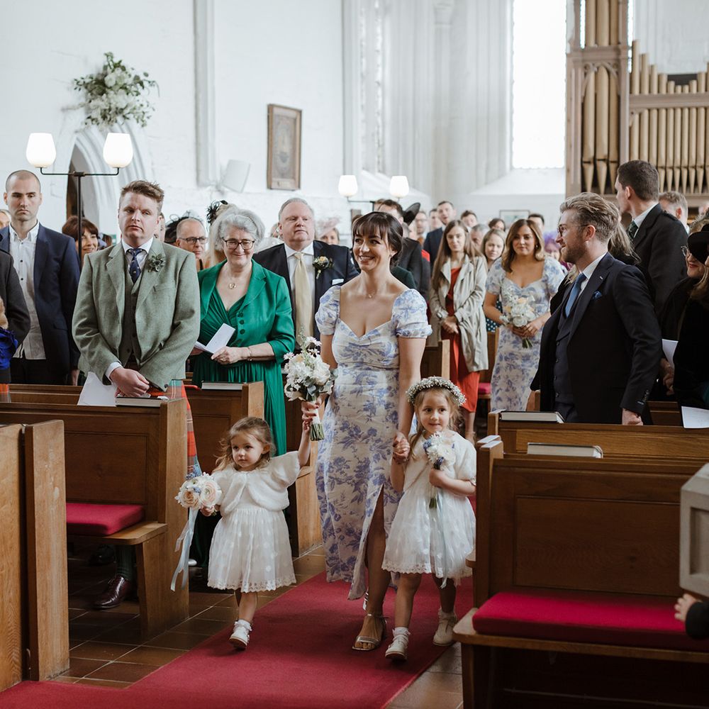 Flower girls and bridesmaids walking down the aisle at church wedding 