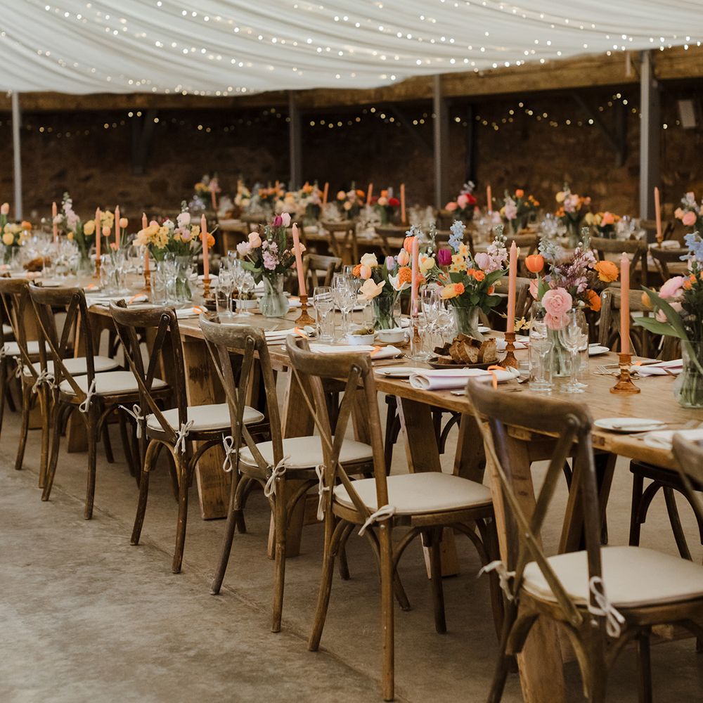 Marquee wedding reception decorated with colourful wedding flower arrangements on the tables 