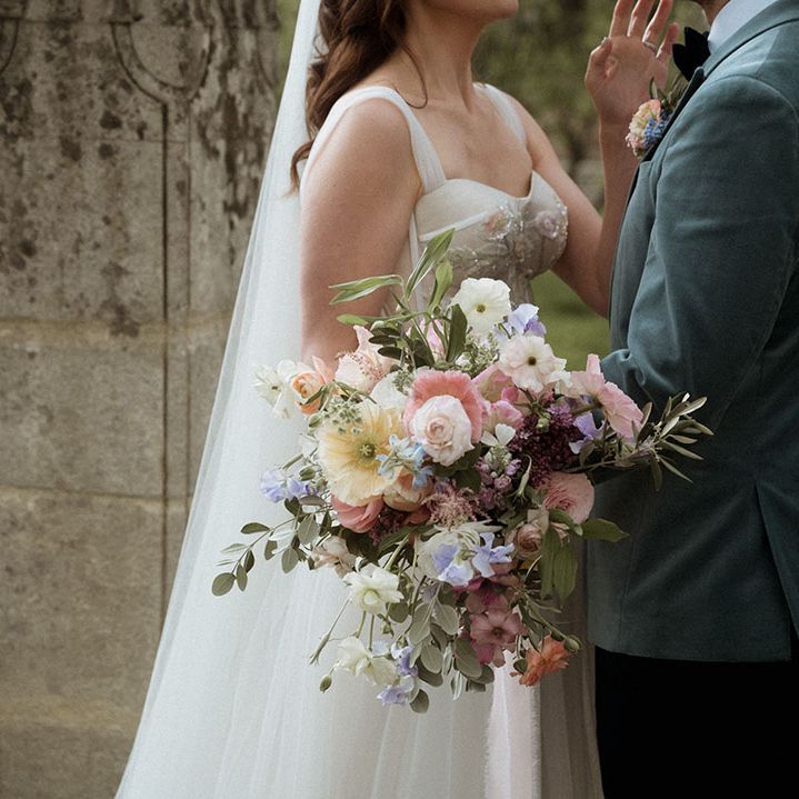 Bride holding pastel yellow, pink, and purple wedding bouquet 