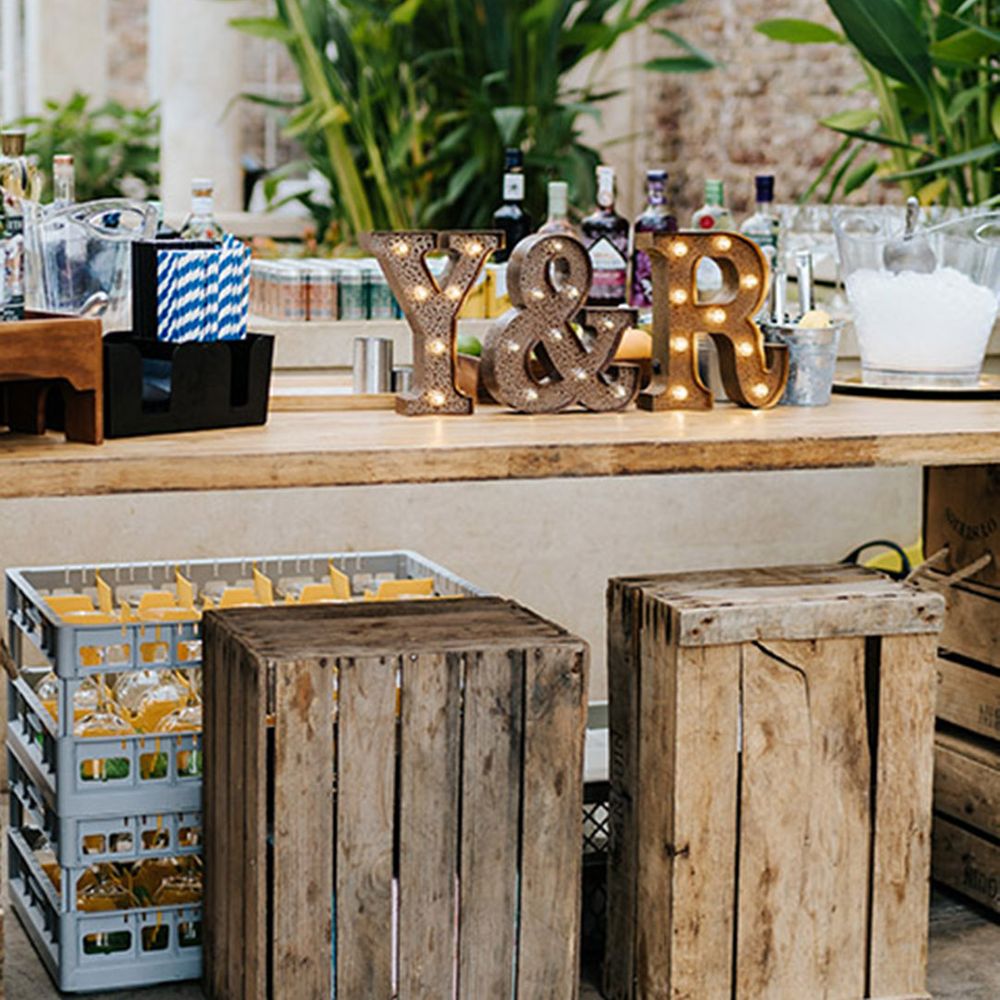 Wedding bar design ideas with letter lights, glasses full of paper straws, cans of mixers and non-alcoholic drinks 