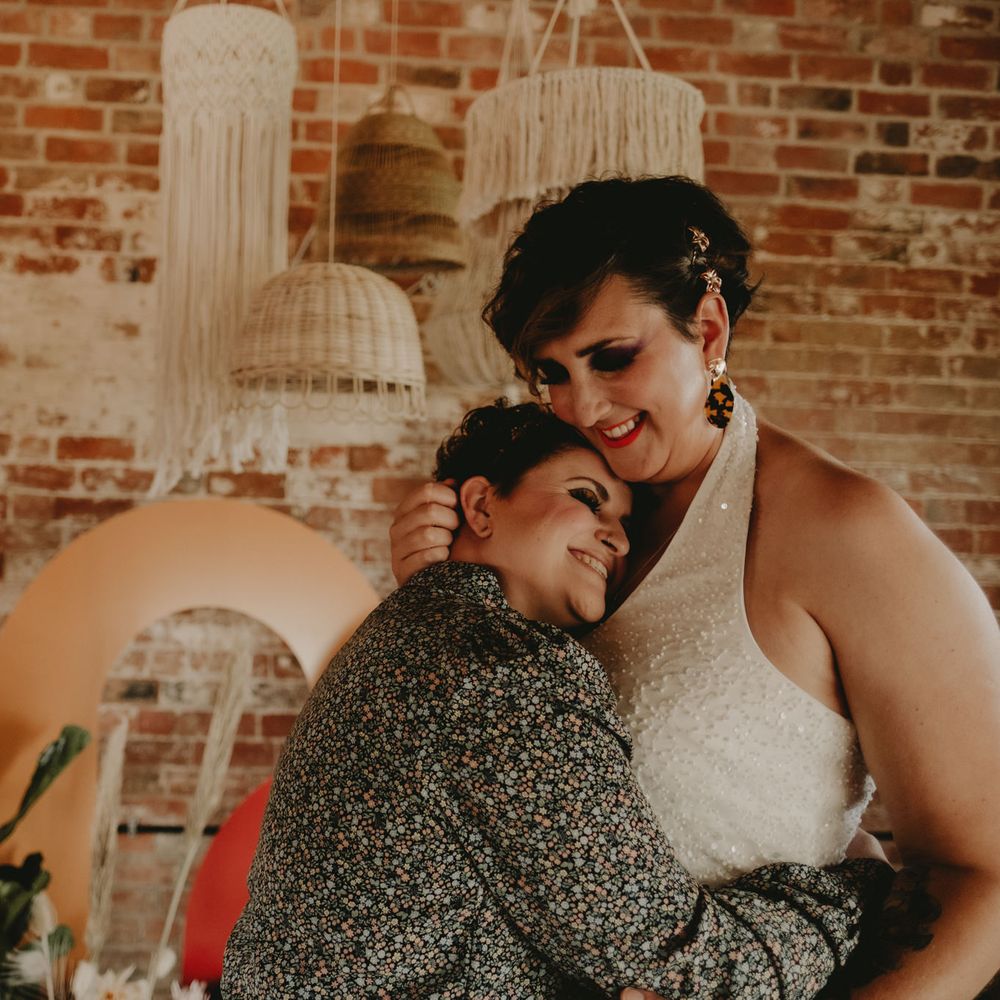 two brides embracing at a 70s LGBT wedding 