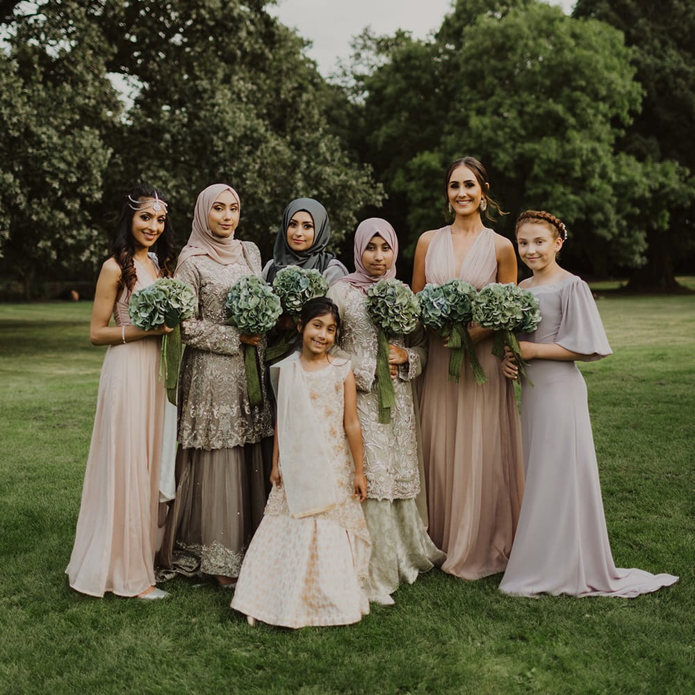 Bridesmaids in pastel grey and pink dresses with green hydrangea bouquets 