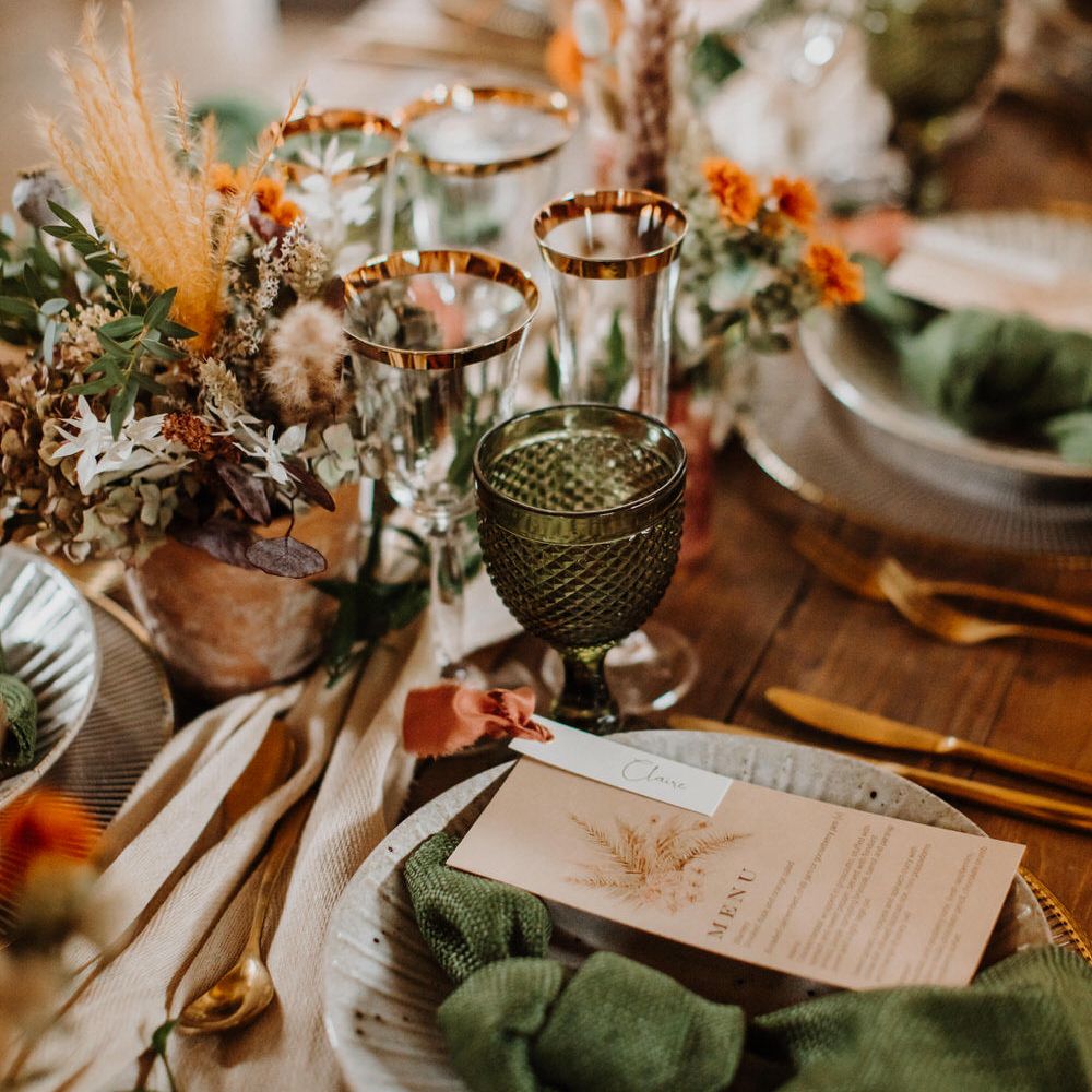 Boho wedding tableware with emerald green glassware and gold rimmed champagne glasses