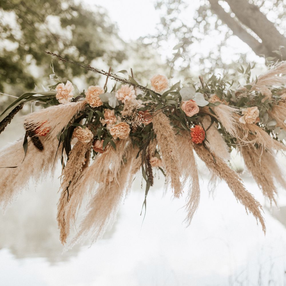 Tied pampas grass with white and orange flowers and green leaf foliage 