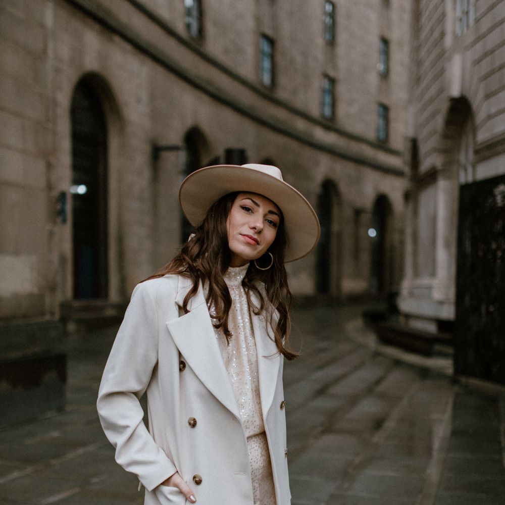 Bride in sequin 'Solange Separates' beige coat and Fedora hat for a stylish city look