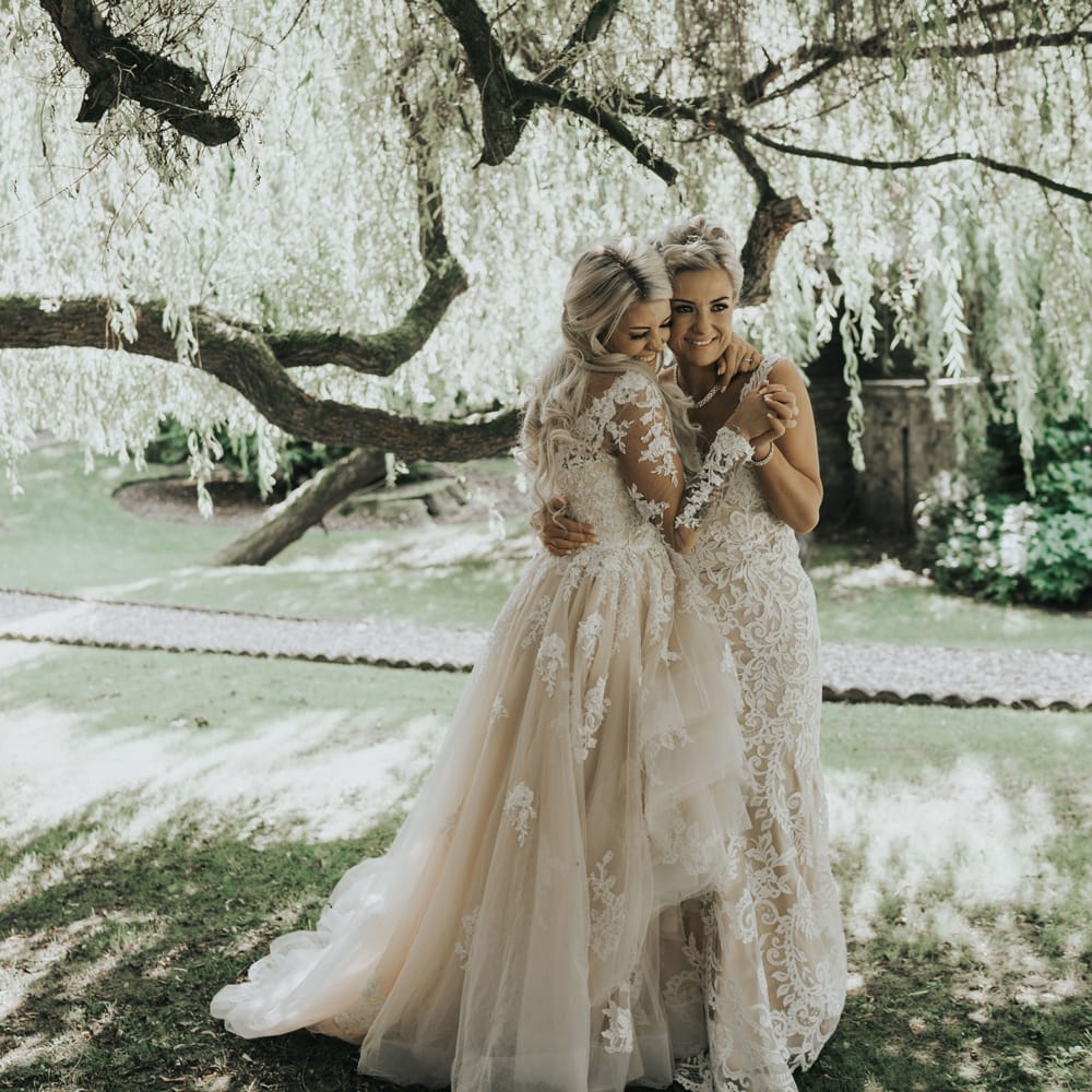 Two brides dance under the trees at Crab & Lobster fairytale wedding.