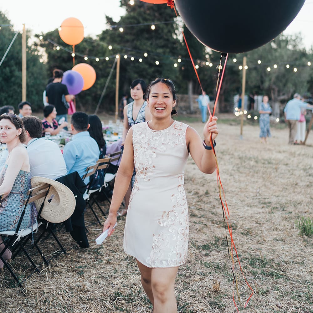 Wedding guest carries large colourful balloons outdoors