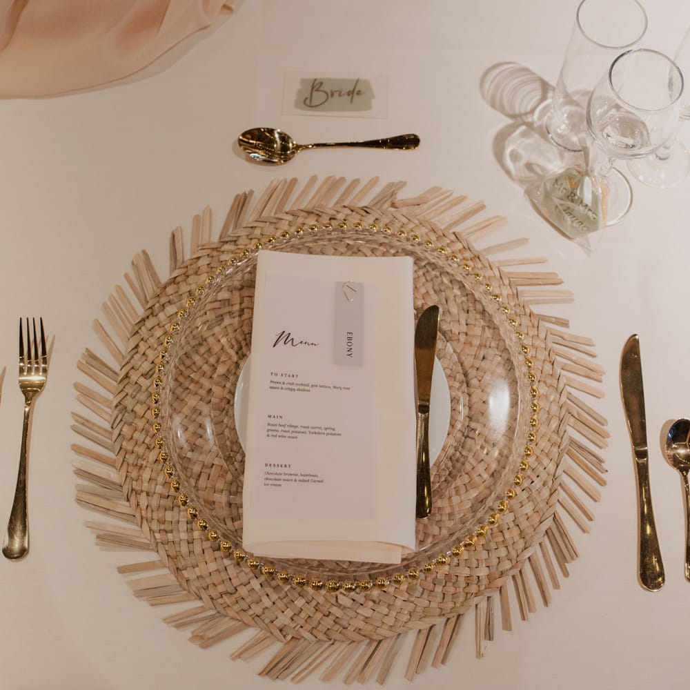 Place setting with wicker placemat, gold rimmed charger plate and gold cutlery