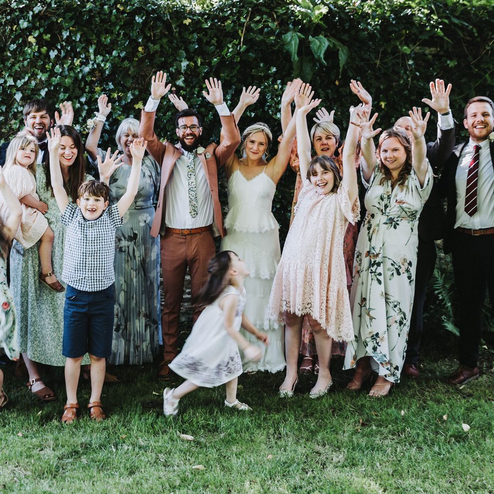 Wedding guests celebrate with one another outdoors for family pictures