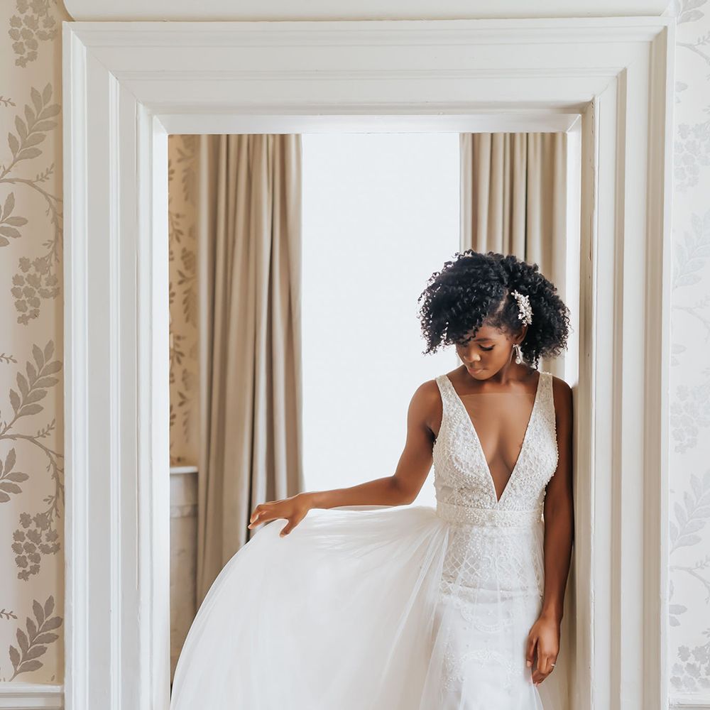 Black bride with naturally curly hair in a plunging neckline wedding dress with tulle skirt 