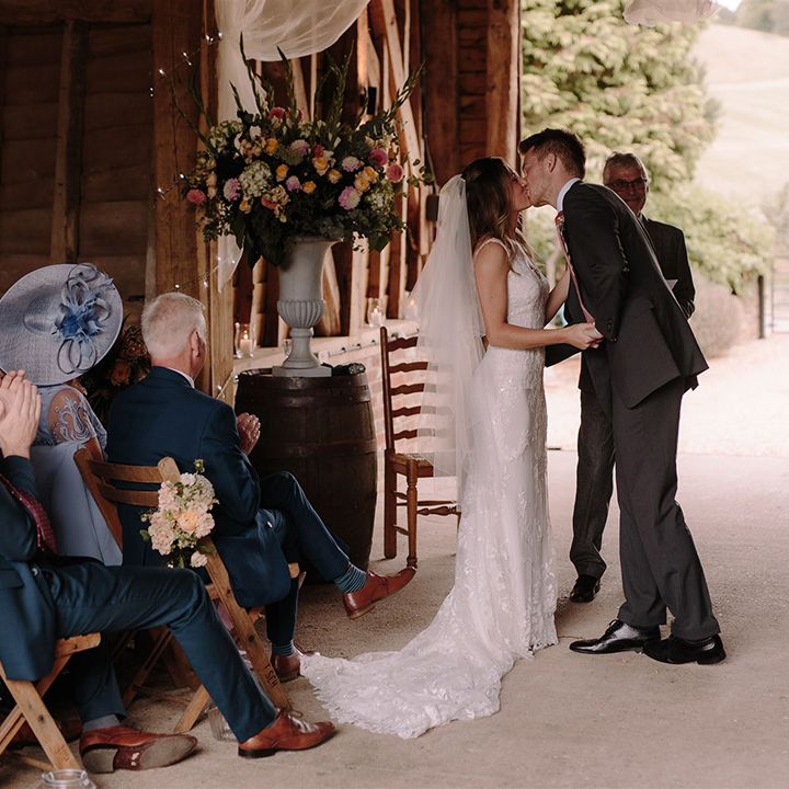 Bride and groom kiss at White Pond Farm barn wedding ceremony
