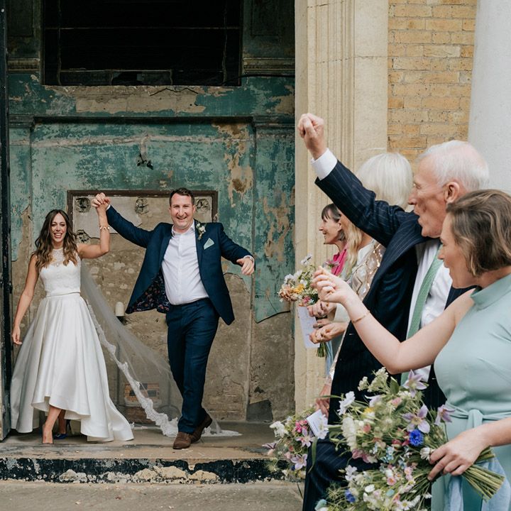 Bride and groom walk through wedding guests as a married couple with bride wearing long lace detailed veil 