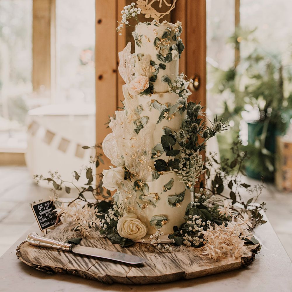 White wedding cake with sage green embellishments and flowers
