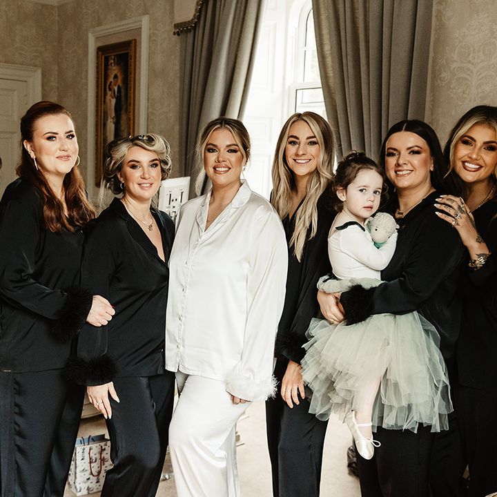 Bride in white satin pyjamas with feather cuff with bridal party in black satin pyjamas with feather cuff