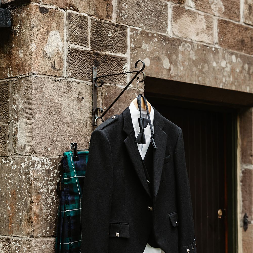 Groom's outfit hanging outside for him including kilt and black tie suit