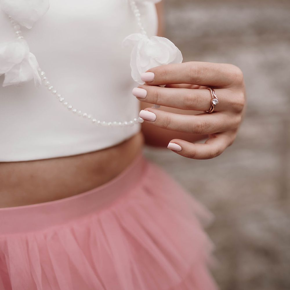 Bride with light pink wedding nail polish holding her statement necklace 