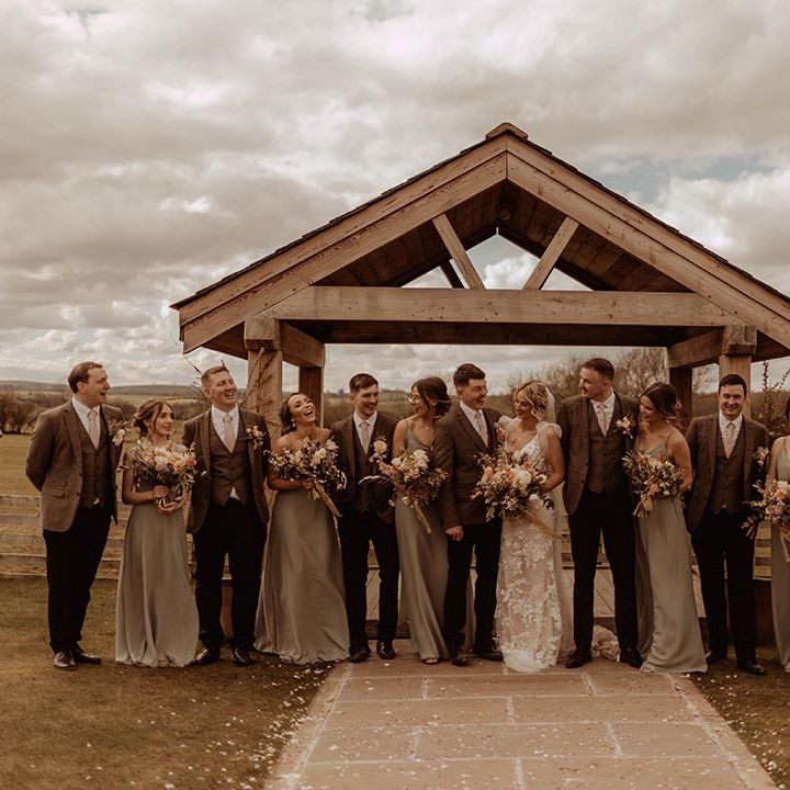 Wedding party smile and pose together for rustic wedding at Eden Barn with orange and neutral colour scheme