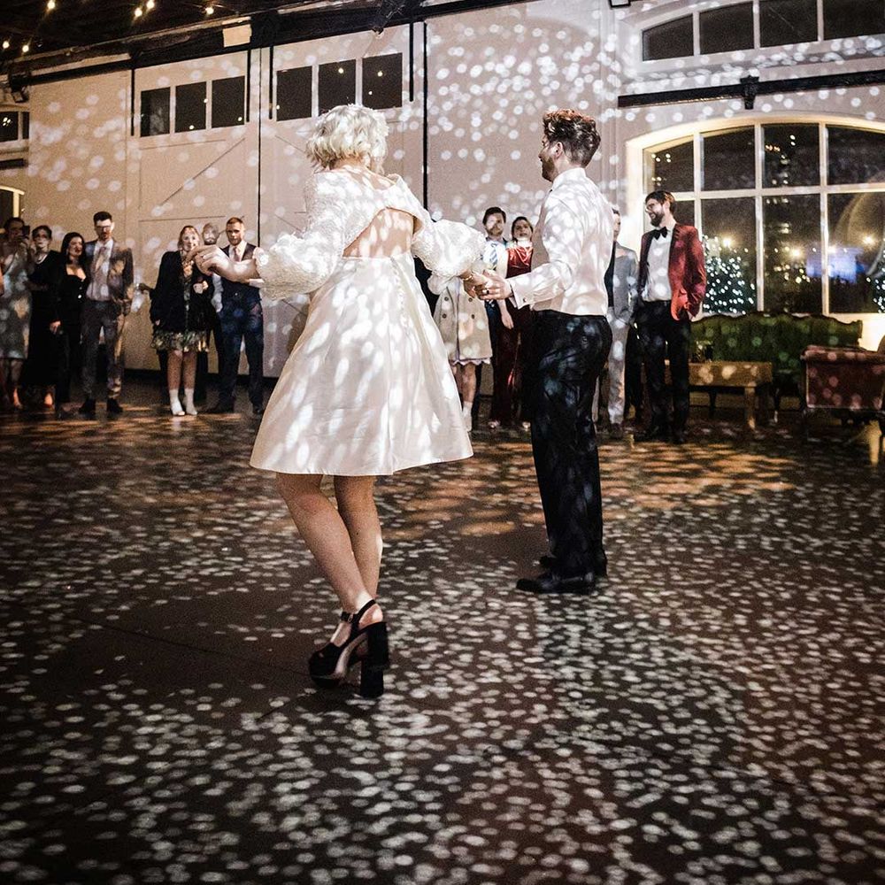 Bride in open back short wedding dress and groom doing their first dance