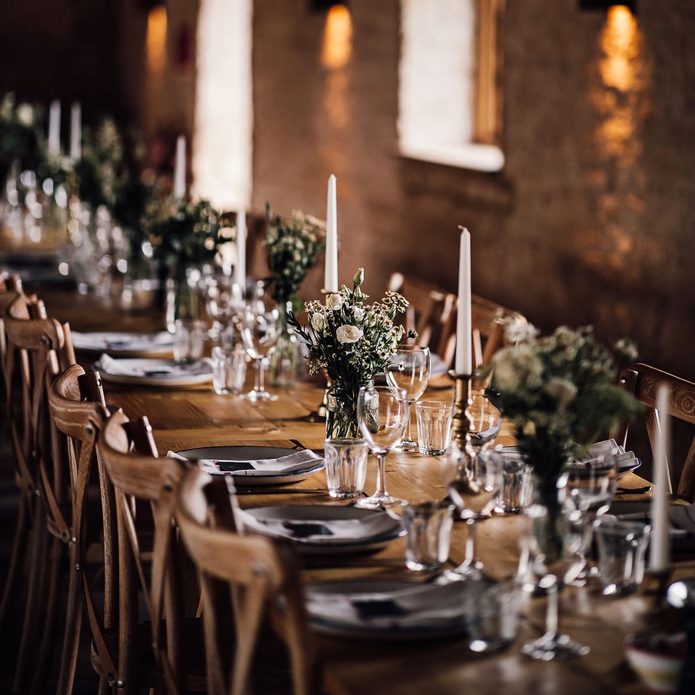 Classic wedding tablescape with white candles in gold candleholders with small arrangements of white flowers 
