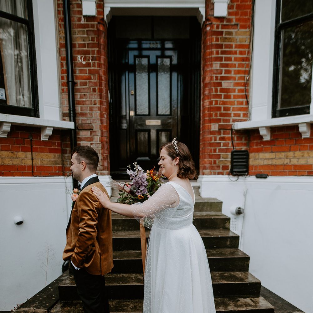 Bride and Groom do a first look outside of their home. Groom wears a burnt orange velvet blazer and Bride wears celestial themed crown and wedding dress