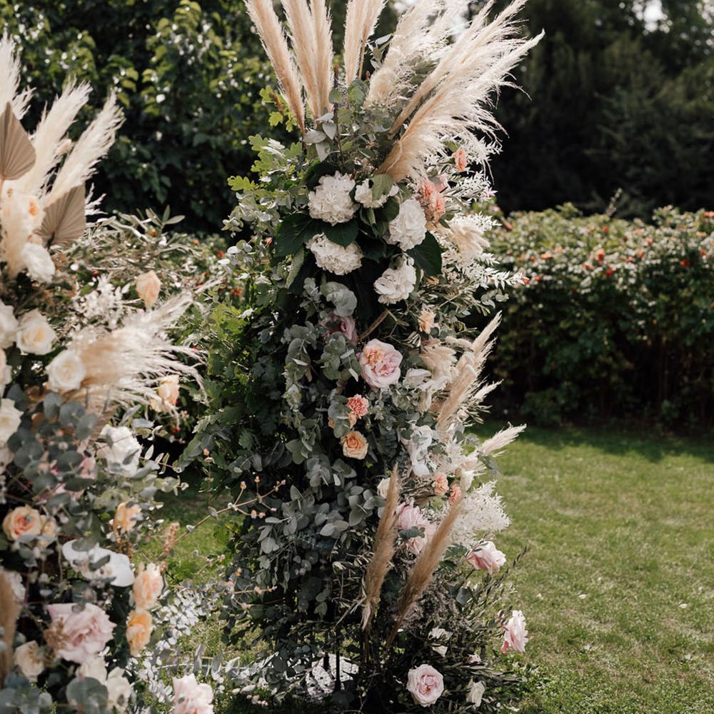 Pink and white wedding flower columns with pampas grass decorate the altar 