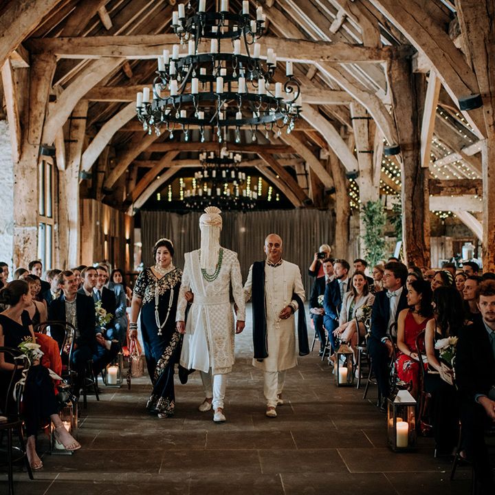 Groom wearing sherwani walks through the Tithe Barn Bolton Abbey surrounded by guests