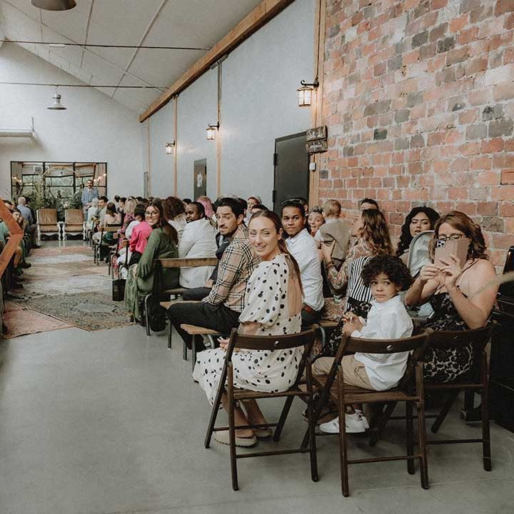 Industrial style ceremony venue complete with exposed brick walls and green foliage to the front 