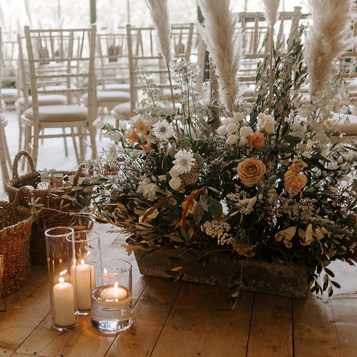 Neutral wedding flowers decorating the aisle with wicker basket of confetti and candles in hurricane vases for decor 