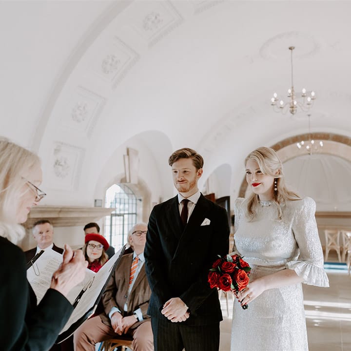 Groom in black tie with the bride in a silver wedding dress with shoulder pads standing in Normanton Church 