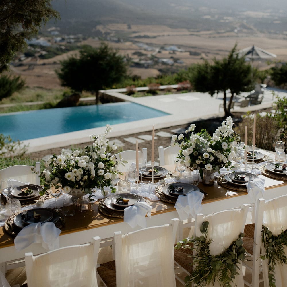 Private villa wedding with white and green floral tablescape, swimming pool and views of the Grecian hills