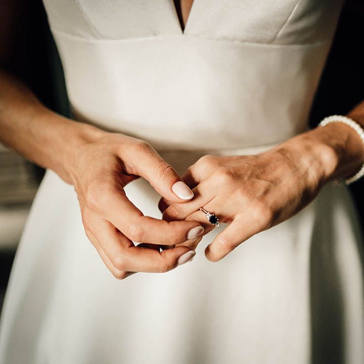 Bride with neutral pink wedding nails with micro french tip wearing her engagement ring 