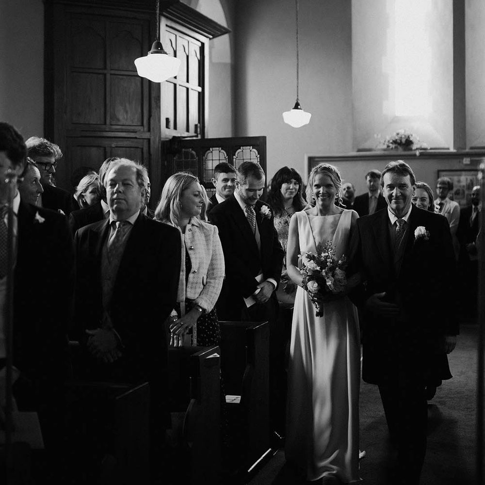 The father of the bride walks the bride down the aisle to the groom 