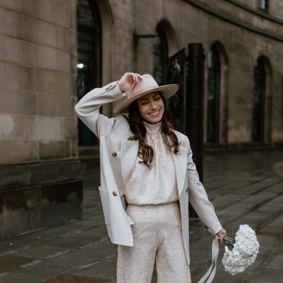 Stylish bride in beige and white neutral outfit holding a hydrangea bouquet 