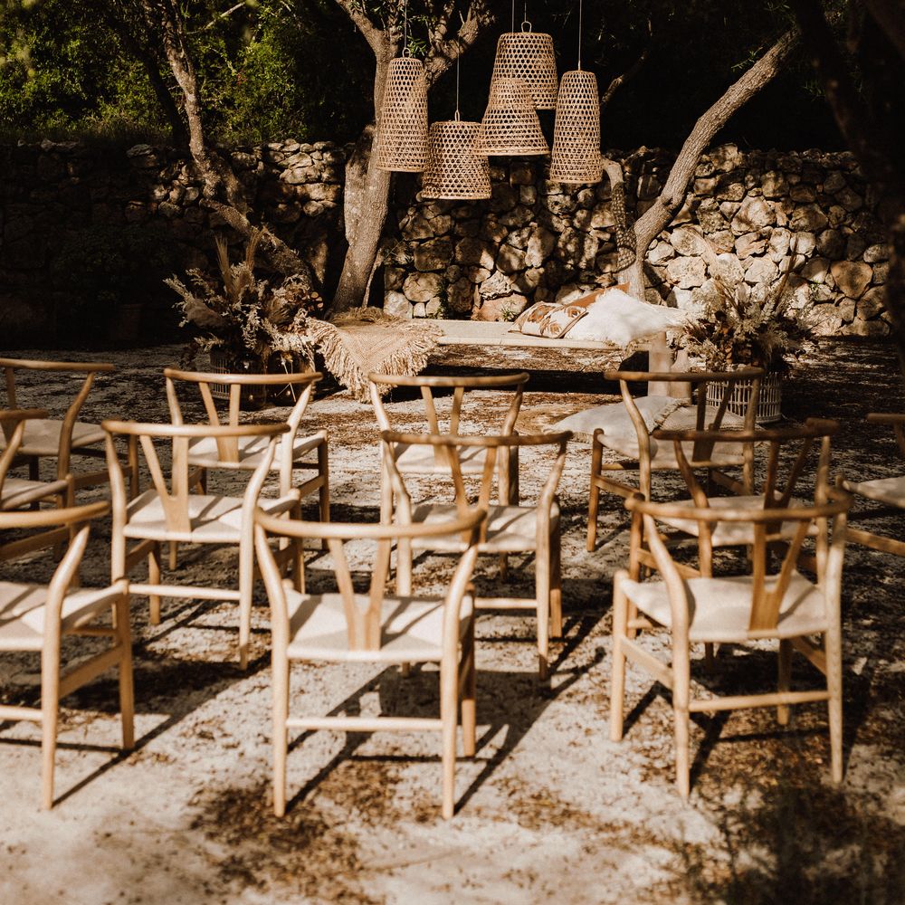 Wooden chairs with wicker lampshades in outdoor ceremony setup