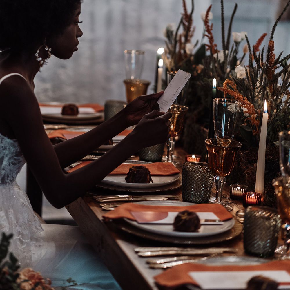 Bride sitting at an intimate candlelit table at Ponden Mill reading the wedding menu 