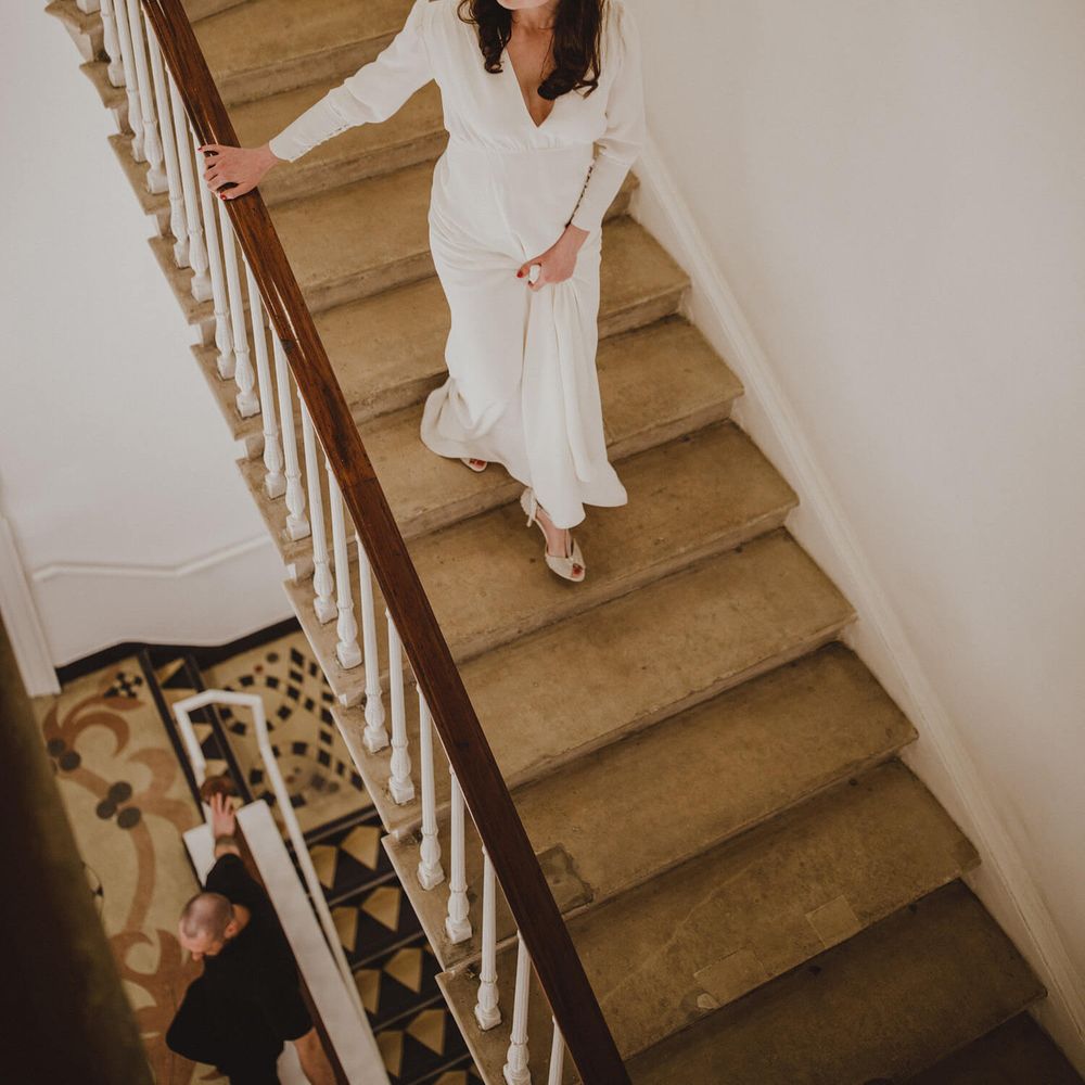 Bride walking down steps wearing long sleeved wedding dress and tiara 