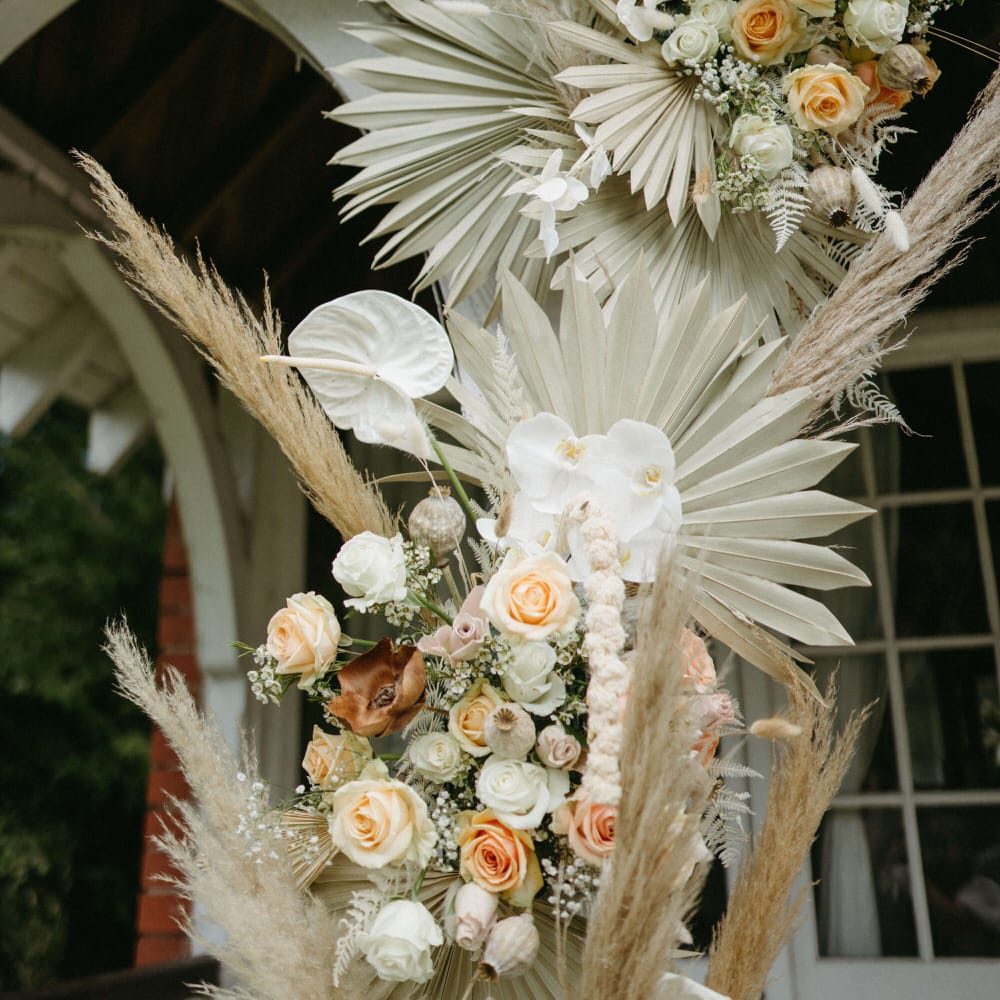 Boho floral archway of dried palms, pampas grass, white anthuriums, roses and orchids at Berwick Lodge
