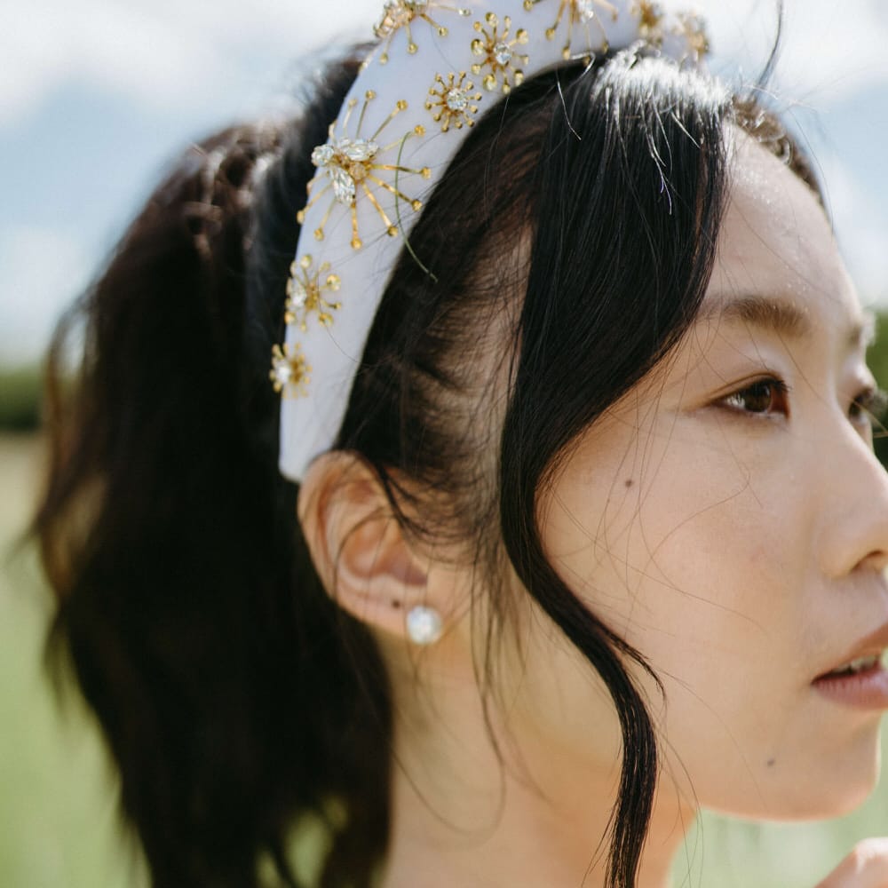 Simple pearl earrings and a white and gold beaded headband for boho bridal style at Berwick Lodge