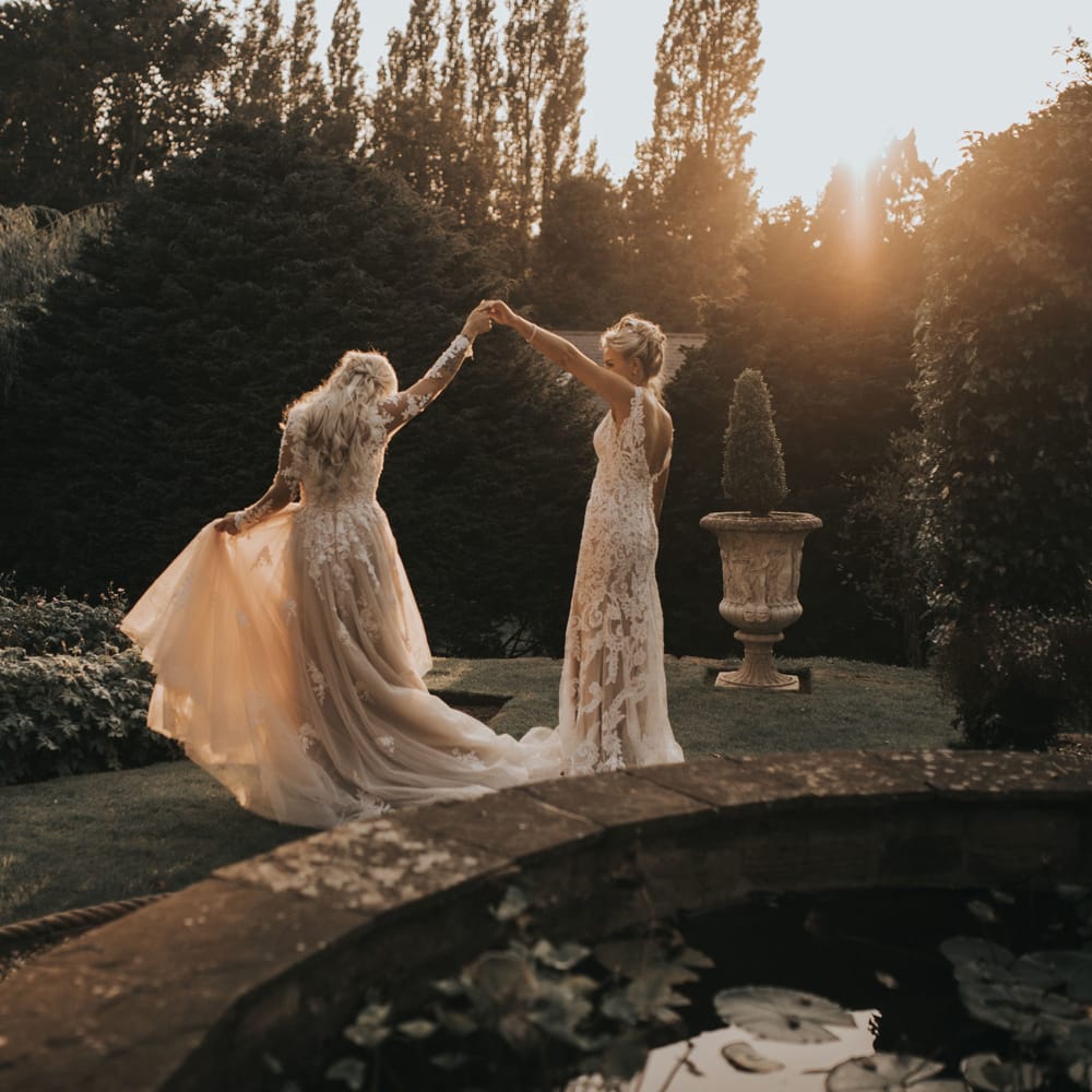 Two brides dance int he grounds of Crab & Lobster at sundown.