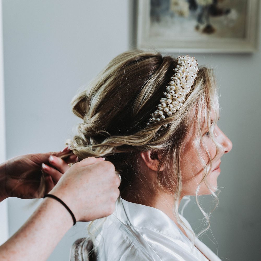 Bride has her blonde hair styled into curls on wedding day with beaded headband