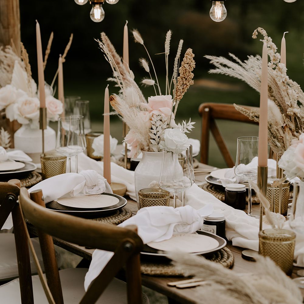 Wedding table decor with taper candles, dried flowers, wicker place matts and hanging light installation 