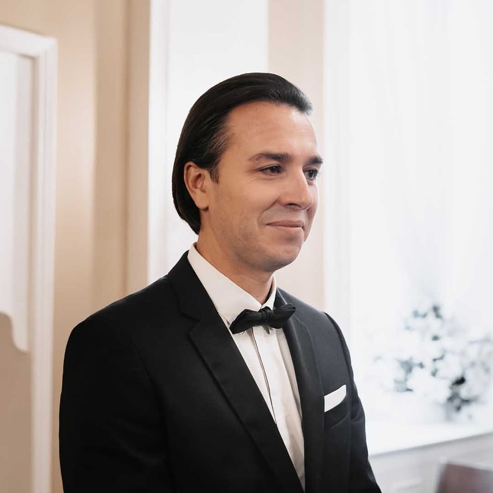 Groom in black sleek suit with black silk bow tie and white shirt 
